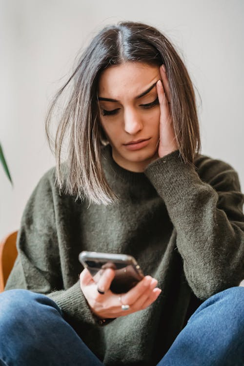 Person looking at a phone screen with a concerned expression while sitting on a couch