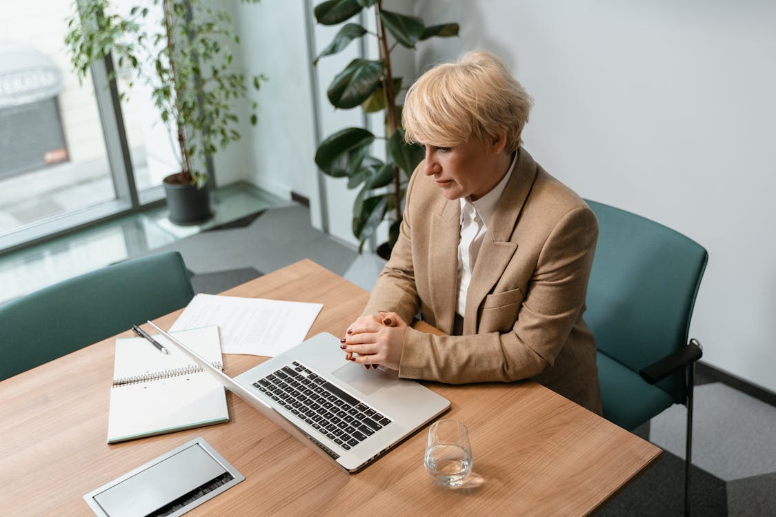 Businessman reviewing documents on a dual-monitor setup in a modern office