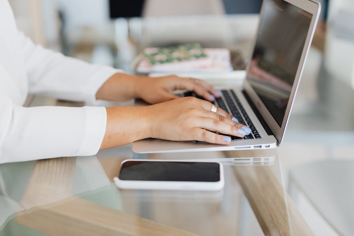 Person at a desk with a checklist and laptop, checking items off one by one